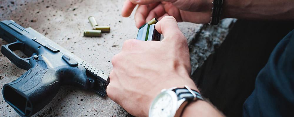 Man loading bullets into a magazine for a handgun.